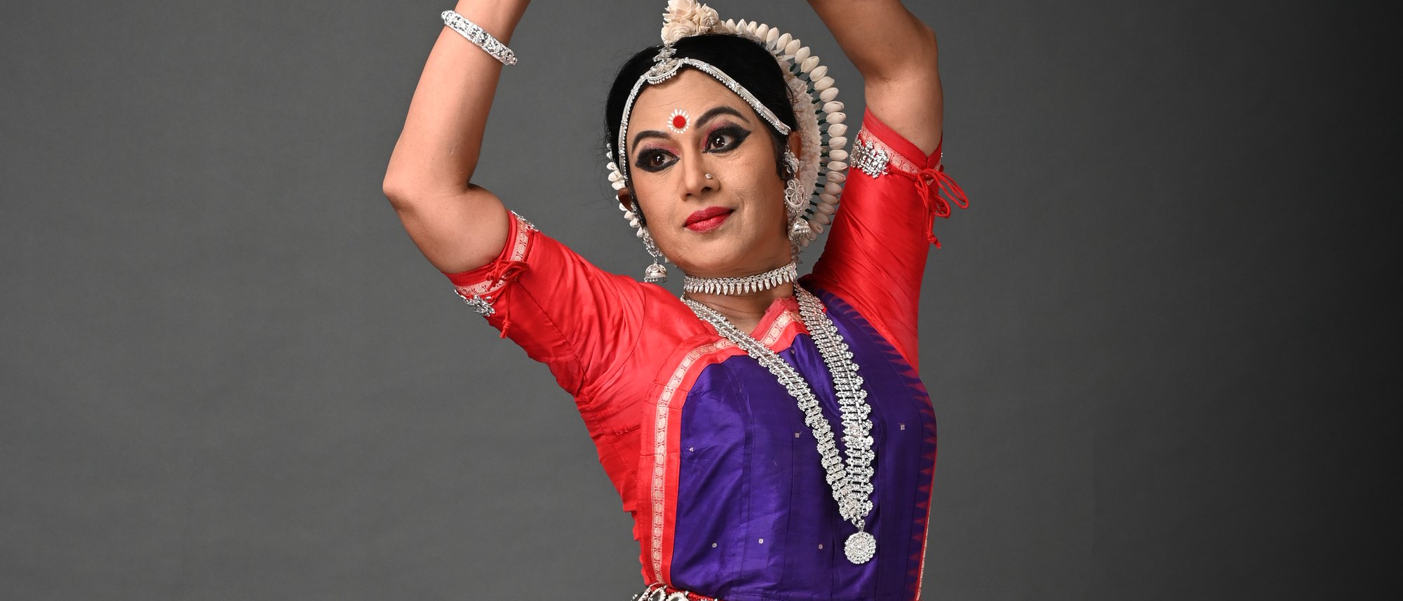 Shubhada Varadkar in an Odissi pose against a dark studio background.