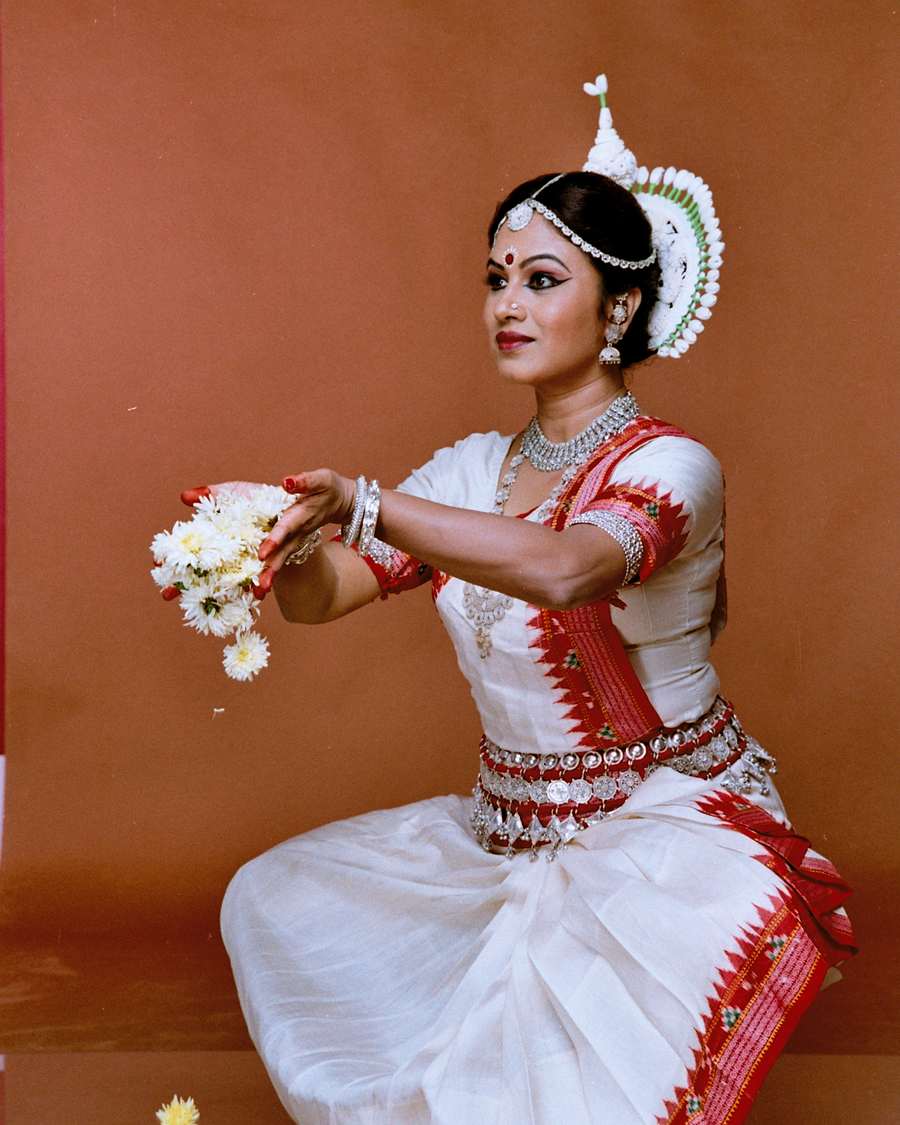 Shubhada Varadkar seated in an Odissi pose, holding flowers.