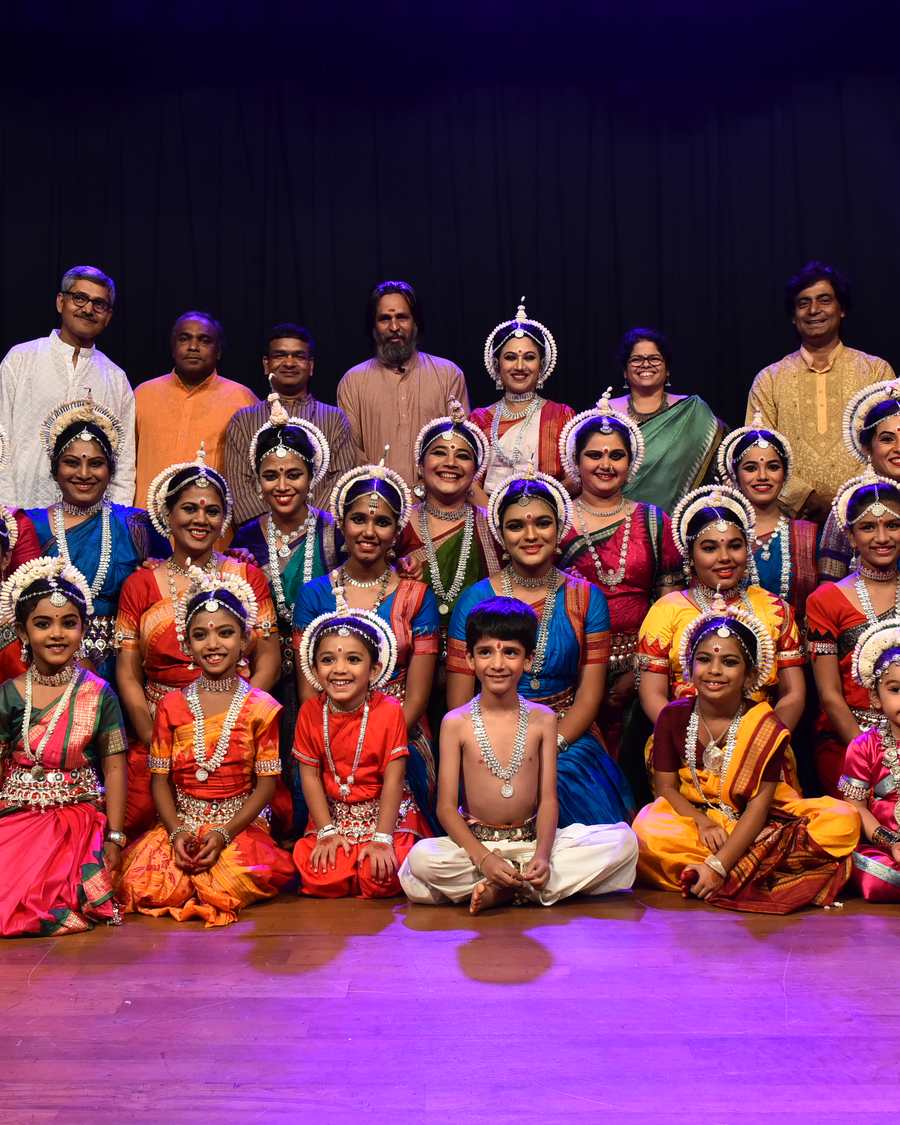 Students in costume seated on stage after a group performance.